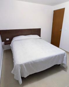 een slaapkamer met een wit bed en een houten hoofdeinde bij El Depa del Puerto in Cancun