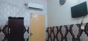 Habitación con puerta y TV en la pared en Hotel Eden Plus Lahore, en Lahore