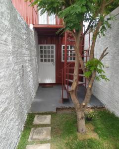 un árbol frente a un edificio con una puerta en Container LB CAXU en Boa Vista