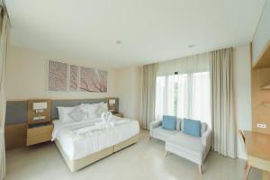 a bedroom with a large white bed and a chair at Movenpick Pool Villa by Hello Pattaya in Na Jomtien