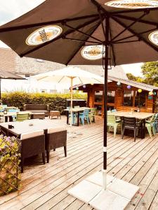 una terraza de madera con mesas, sillas y sombrilla en Gasthof Sonnental en Winterberg