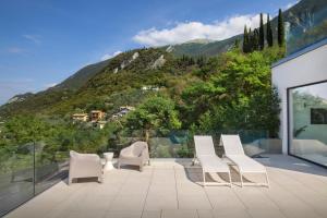 a patio with white chairs and a view of a mountain at Residenza Dimora Privata With Pool in Malcesine