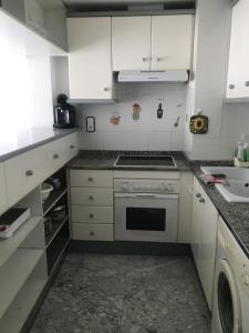 een keuken met witte kasten, een fornuis en een wastafel bij Perfect apartment near Port Aventura, beach in Salou