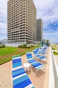 uma fila de espreguiçadeiras azuis e brancas em frente a um edifício alto em Glorious Ocean Sunset Views 2 Bed 2 Bath Condo em Daytona Beach