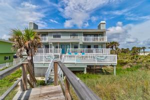 a house on the beach with a wooden boardwalk at Tipsy Turtle Direct Oceanfront in Palm Coast