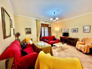 sala de estar con sofá rojo y sillas en Casa Los Canos, en Úbeda