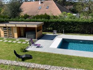 einen Hof mit Pool und zwei Stühlen und ein Haus in der Unterkunft Art de l'Ô in Neufchâtel-Hardelot