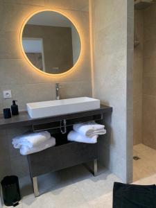 uma casa de banho com lavatório, espelho e toalhas em Art de l'Ô em Neufchâtel-Hardelot