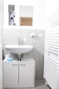 W łazience znajduje się biała umywalka i lustro. w obiekcie Marstall Apartmenthaus Kassel w mieście Kassel