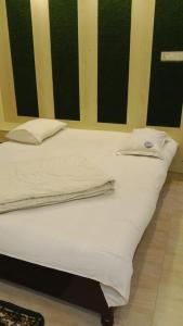 a bed with white sheets and pillows in a room at Hotel The Grand Sandy in Cox's Bazar