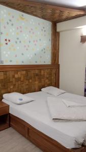 ein Schlafzimmer mit einem weißen Bett mit Blumen an der Wand in der Unterkunft Hotel The Grand Sandy in Cox's Bazar
