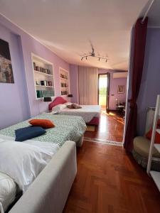 2 letti in una camera con pareti viola e pavimenti in legno di L'albero Del Pepe a Fiano Romano