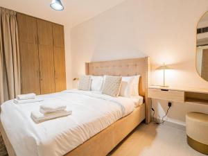 a bedroom with a large white bed and a desk at Noble looking 2 Bed only five minutes to Metro in Dubai