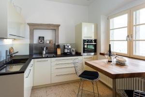 uma cozinha com armários brancos e uma mesa de madeira com uma cadeira em Appartement im Grünweinhof em Montagna