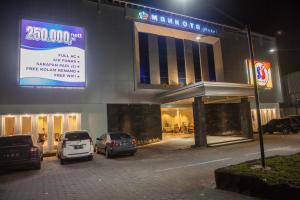 Un estacionamiento con autos estacionados frente a un edificio. en Mahkota Hotel, en Genteng-kulon