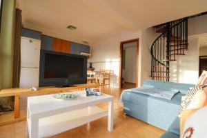 salon z niebieską kanapą i telewizorem w obiekcie Sardina attic flat pool&solarium w mieście Gáldar