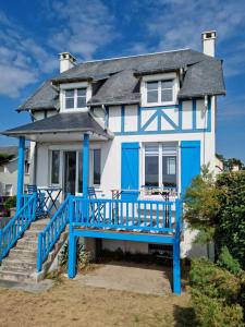 una casa azul y blanca con un banco azul delante en Villa La Hautaise vue sur mer, en Hauteville-sur-Mer