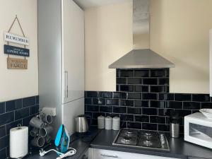 a kitchen with a stove and a black tiled wall at Urban view in Doncaster