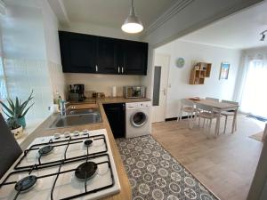 a kitchen with a stove top oven next to a sink at Ty Gavrinis - T2- Centre Bourg - 100m de la mer in Larmor-Baden