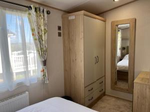 a bedroom with a wooden cabinet and a mirror at 3 Bedroom Caravan MC34, Lower Hyde, Shanklin, Isle of Wight in Shanklin