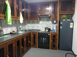 a kitchen with wooden cabinets and a black refrigerator at Markhaba in Samarkand