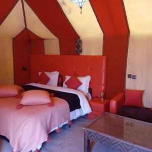 a red room with two beds and a table at Fabulous Desert Camp in Merzouga