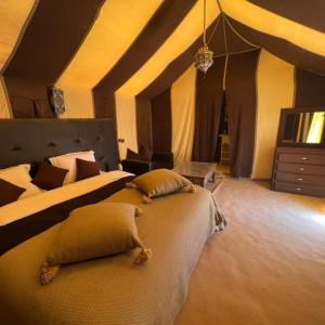 - une grande chambre avec 2 lits et une commode dans l'établissement Fabulous Desert Camp, à Merzouga