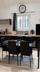 a dining room with a table and chairs and a clock at DUPLEX COSY Confort PISCINE in Caderousse