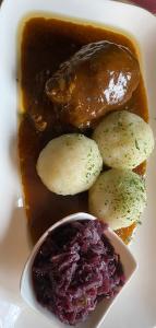 a plate of food with meat and potatoes and a sauce at Buddes Wirtshaus in Drolshagen