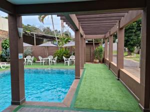 a swimming pool with a wooden pergola and a swimming pool at Hotel Rouver in Foz do Iguaçu