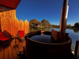 a wooden deck with a hot tub and chairs on a body of water at L'INDUS - Le Domaine Wambrechies in Wambrechies