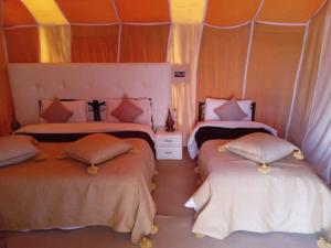 two beds in a room with orange and pink at Fabulous Desert Camp in Merzouga