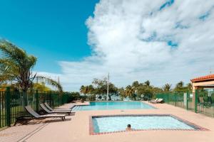 a swimming pool with chairs and a fence at Oceania Apartments at Arecibo 681 Ocean Drive in Arecibo