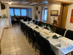 ein Zimmer mit einem langen Tisch mit Stühlen und einem Tischler in der Unterkunft Buddes Wirtshaus in Drolshagen