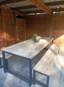 una mesa de picnic y bancos en un patio en Woning gelegen in rustige bosrijke omgeving, en Wingene