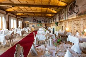 a dining room with white tables and chairs at Berghütte Sommerstall in Redagno