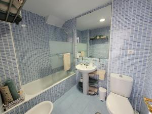 Baño de azulejos azules con aseo y lavamanos en La Arena, en Miengo