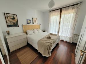 a bedroom with a bed with white sheets and two windows at La Arena in Miengo