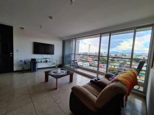 - un salon avec un canapé et une grande fenêtre dans l'établissement Apartment with city view in Oasis de San José, à San José