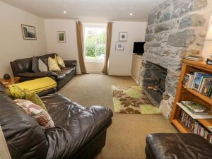 sala de estar con sofá de cuero y chimenea de piedra en Tyn Llwyn, en Talsarnau
