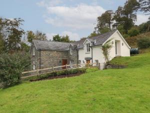una casa de piedra en una colina con un patio en Tyn Llwyn, en Talsarnau