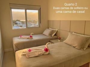 2 Betten in einem Zimmer mit Schwänen darauf in der Unterkunft Lindo e aconchegante apartamento a poucos mts da Praia Grande - Governador Celso Ramos in Governador Celso Ramos
