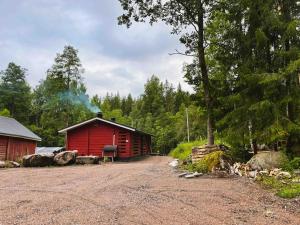 a red cabin in the middle of a forest at Katiskosken joenrantamökki in Hämeenlinna