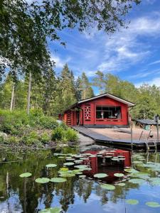 a red cabin with lily pads in the water at Katiskosken joenrantamökki in Hämeenlinna