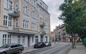 two cars parked on a city street with buildings at Apartamenty Chorzów obok Parku Śląskiego in Chorzów