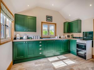 a green kitchen with green cabinets and a window at Stable Barn in Saint Lawrence