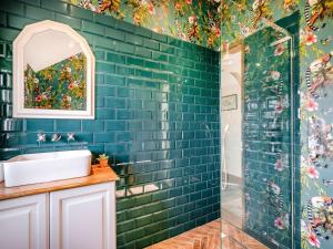 een badkamer met een groene betegelde muur en een wastafel bij Stable Barn in Saint Lawrence