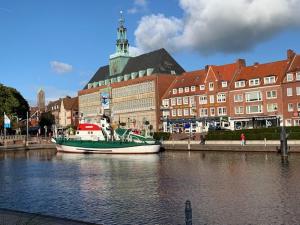 een boot is aangemeerd in een rivier voor gebouwen bij Ferienwohnung Engelke in Emden