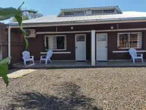 uma casa castanha com duas cadeiras brancas e uma mesa em La Cascada 2 em Posadas