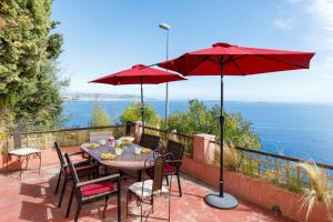 un patio con una mesa con sillas y una sombrilla en Les Oules Vertes YourHostHelper classé 3 étoiles en Théoule-sur-Mer